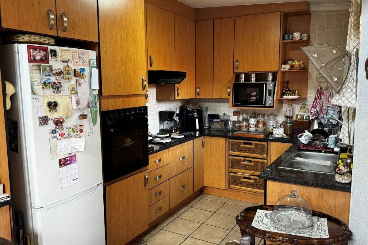 A functional kitchen featuring wood-finish cabinetry, dark granite countertops, a built-in oven, and a stainless steel sink with tiled splashbacks.