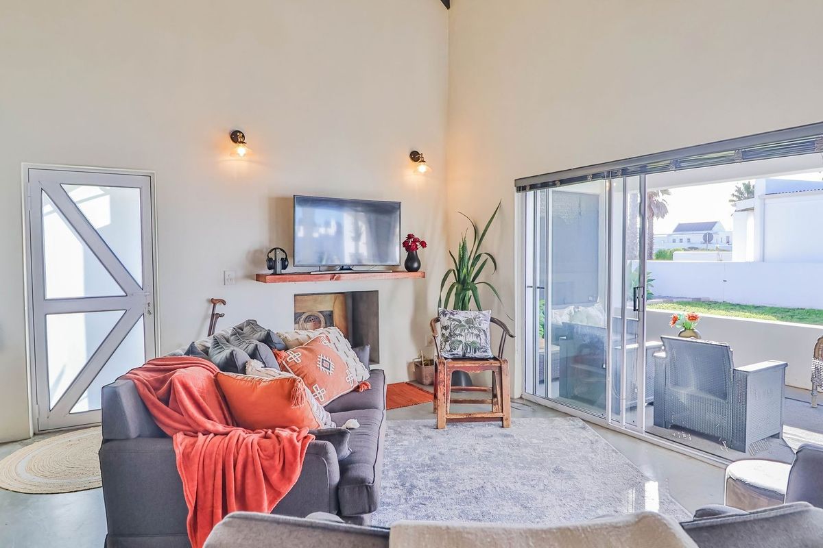 A bright living room featuring high ceilings, a built-in fireplace, and large sliding glass doors that open onto a covered patio area.