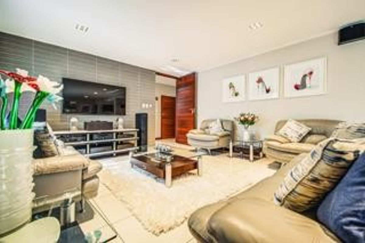 A well-maintained living room featuring a textured feature wall, tiled flooring, and recessed ceiling lighting, creating a comfortable and modern living space.