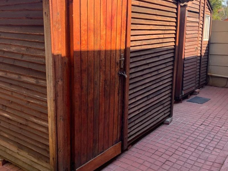 External timber utility sheds situated on a paved area, providing additional storage space for the property.