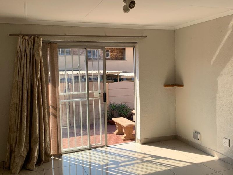 Bright and spacious living area featuring neutral tiled flooring and a sliding glass door providing direct access to the outdoor patio area.
