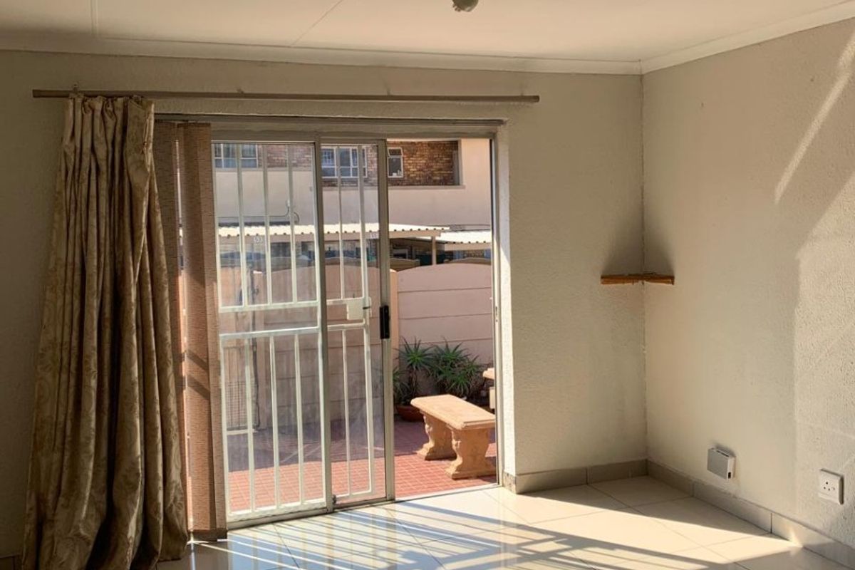Bright and spacious living area featuring neutral tiled flooring and a sliding glass door providing direct access to the outdoor patio area.