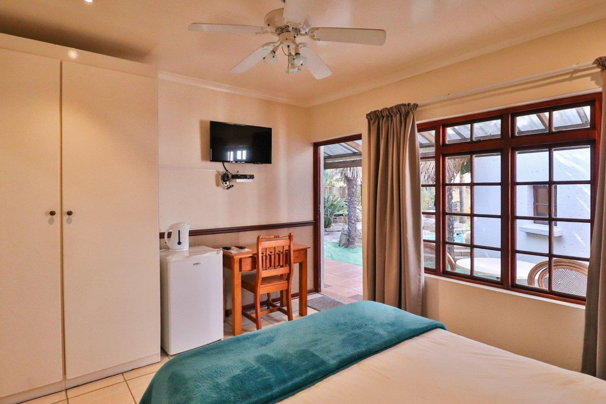 A bedroom featuring built-in cabinetry, a ceiling fan, and direct access to an outdoor patio area through a glass-paned door.