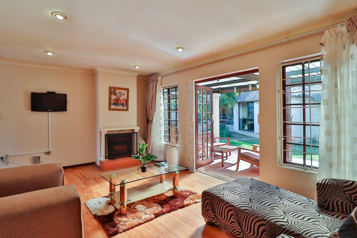 A comfortable living room featuring a built-in fireplace, wooden flooring, and double doors opening onto a covered patio area.