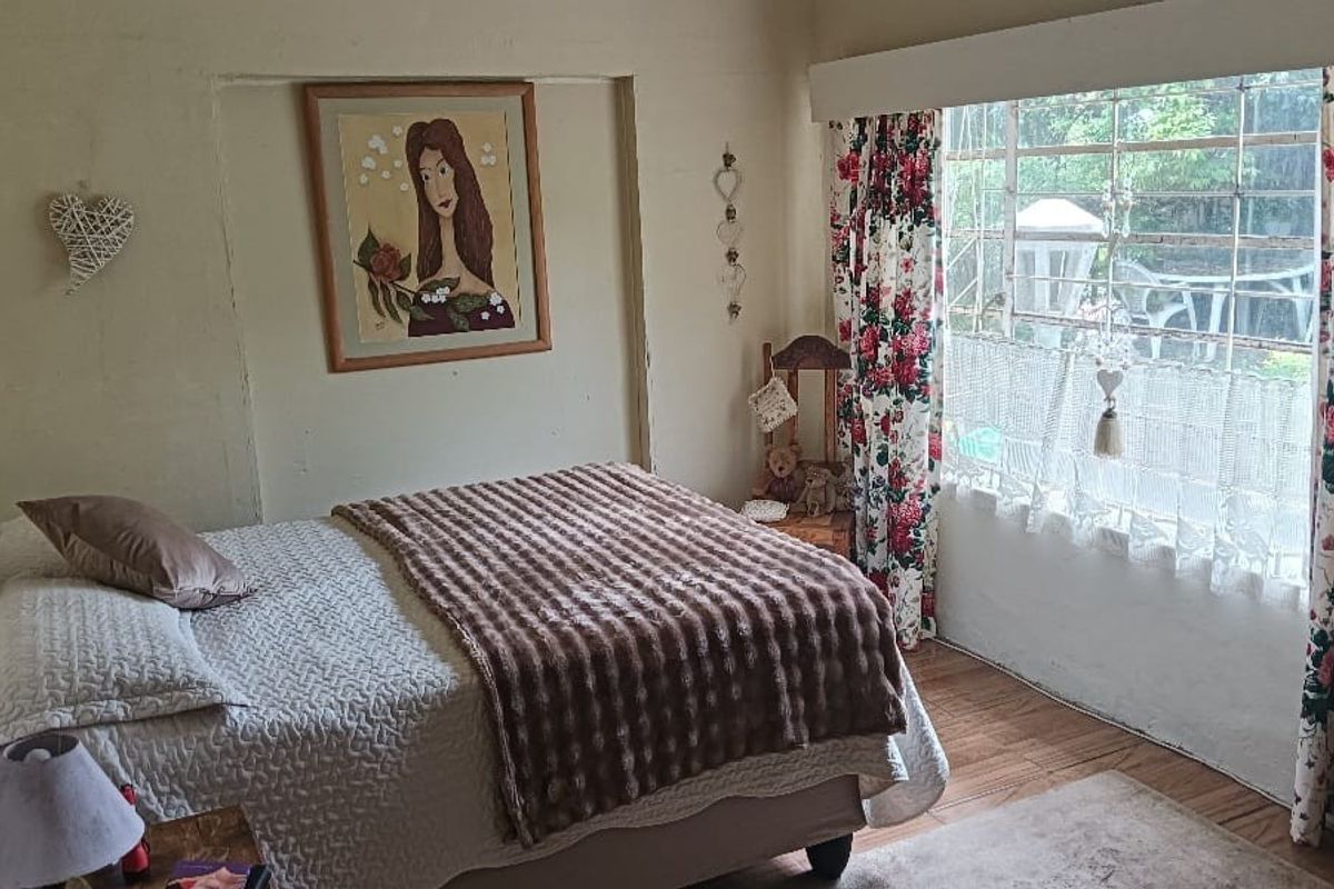 A bedroom featuring a large window with security bars, neutral wall finishes, and wood-look flooring.