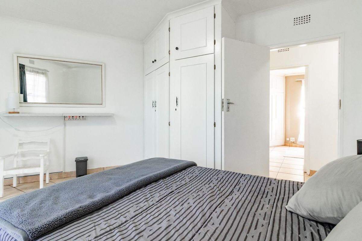 A bedroom featuring built-in white cabinetry, tiled flooring, and a doorway leading to an adjacent room.