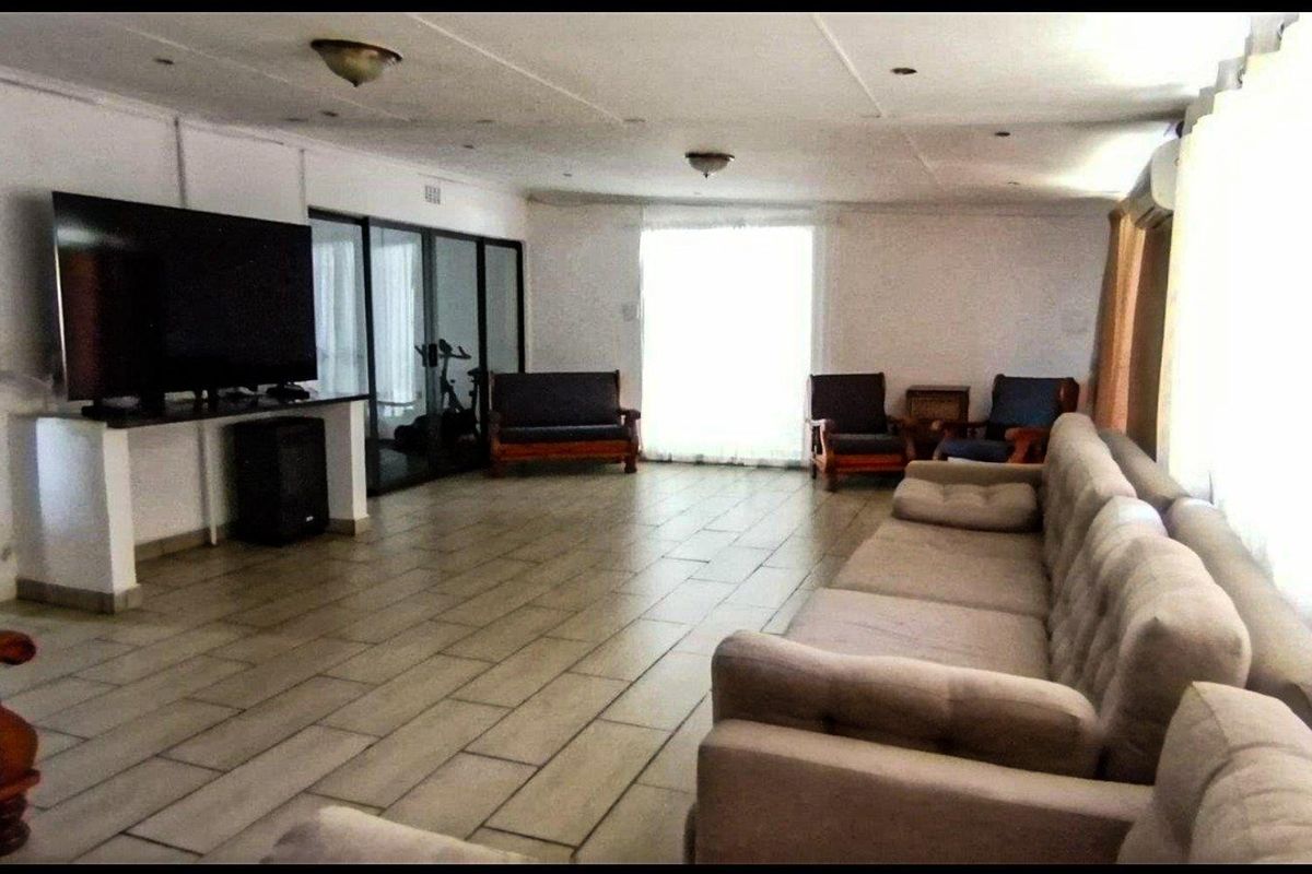 Spacious living area featuring tiled flooring, recessed lighting, and sliding glass doors leading to an adjacent space.