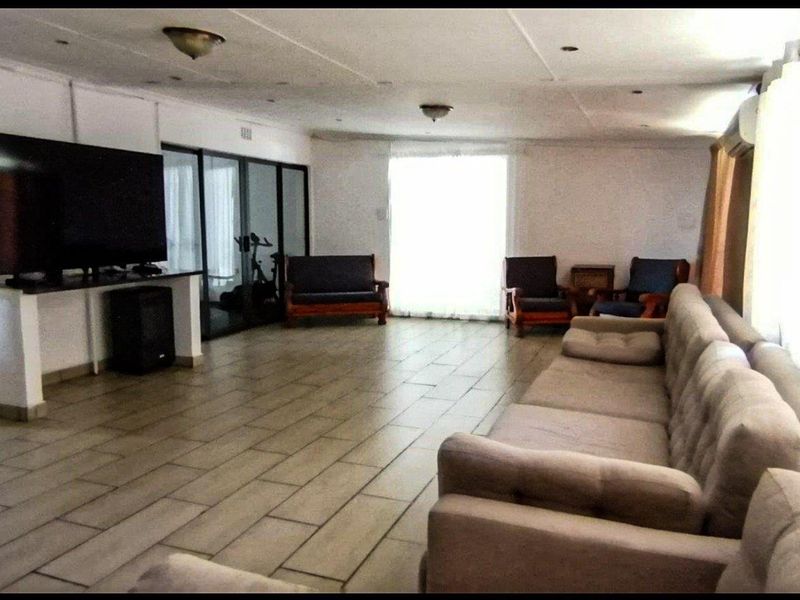 Spacious living area featuring tiled flooring, recessed lighting, and sliding glass doors leading to an adjacent space.