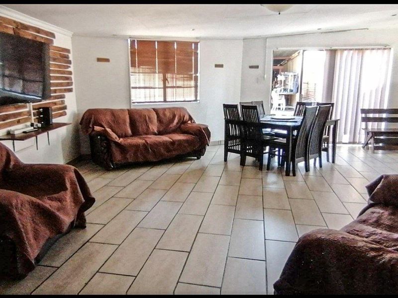 Spacious open-plan living and dining area featuring tiled flooring, a timber accent wall, and sliding door access to the outdoor space.