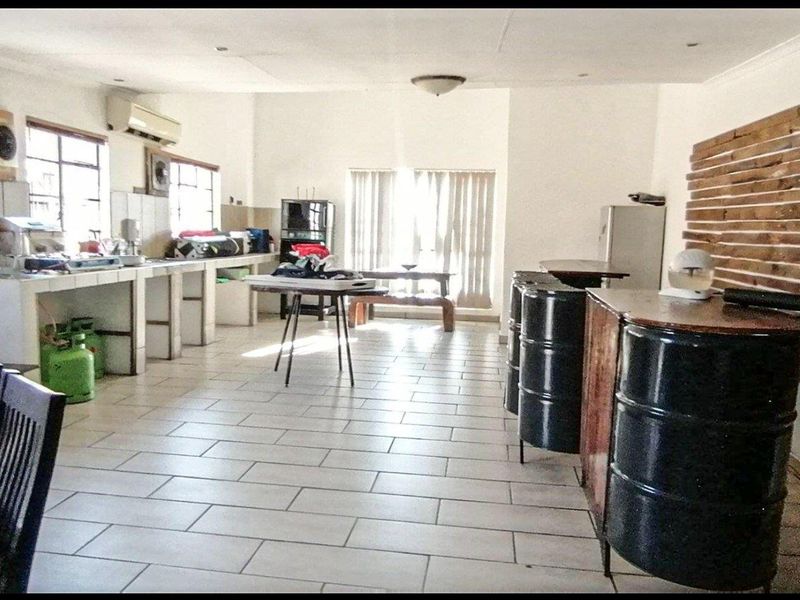 Spacious open-plan living and kitchen area featuring tiled flooring, built-in counter space, and timber wall accents, offering significant potential for modernization.