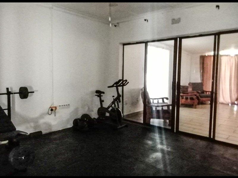 A dedicated gym space featuring durable rubber flooring and large sliding glass doors that provide a view into the adjacent living area.