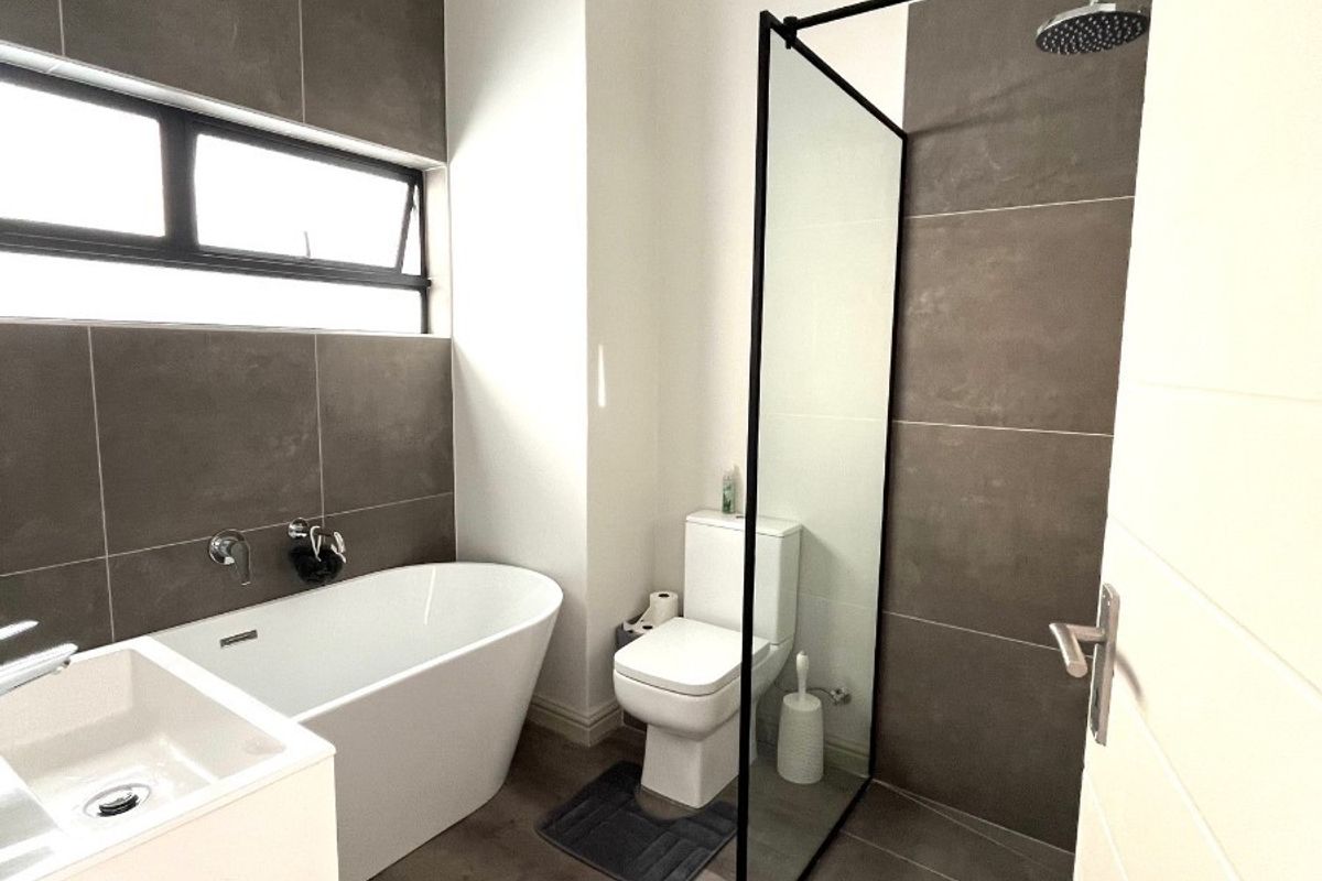 Modern bathroom featuring a sleek freestanding bathtub, a spacious walk-in shower with a glass screen, and contemporary tiled finishes.