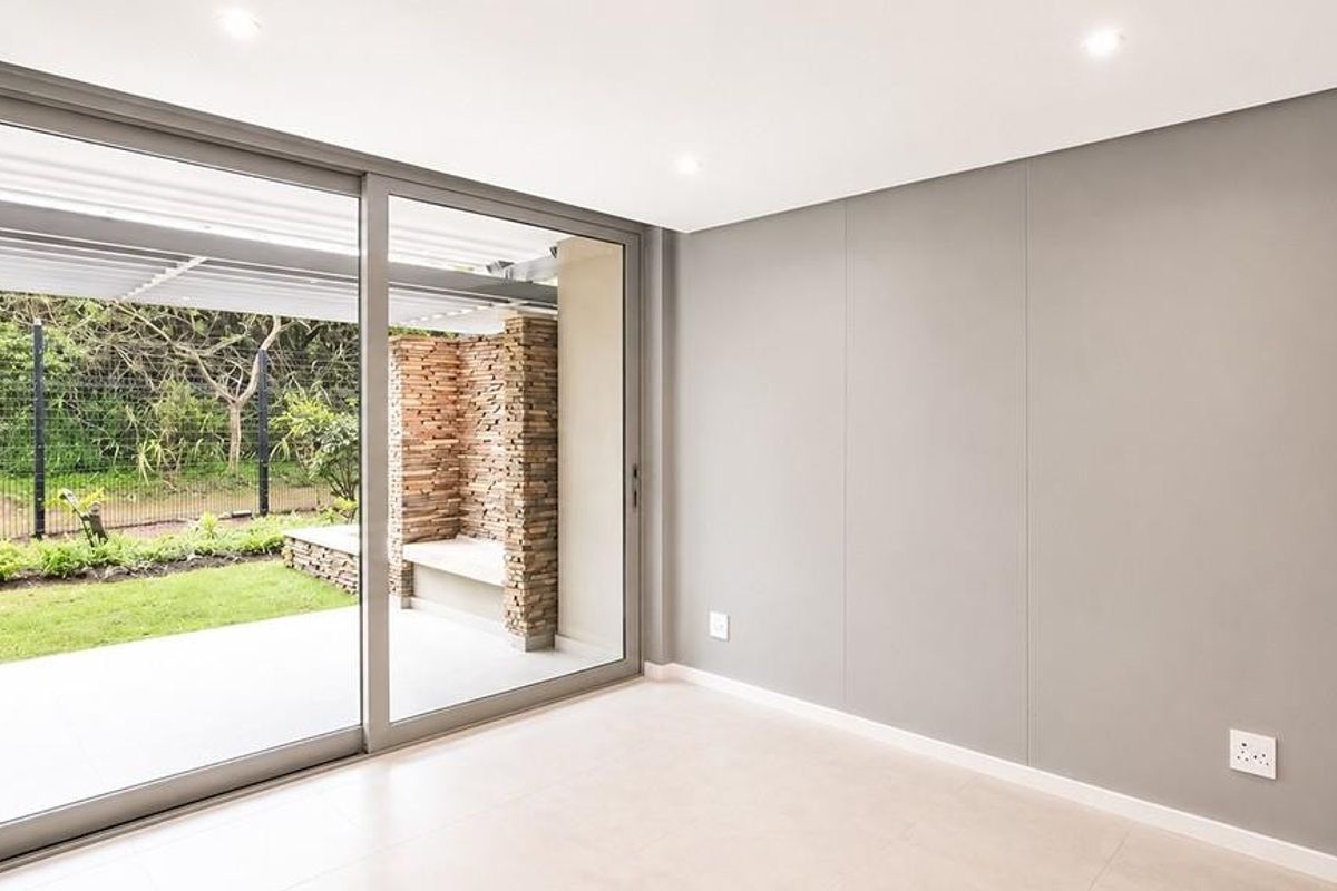 A bright, modern living area featuring large sliding glass doors that open onto a private patio and garden space.