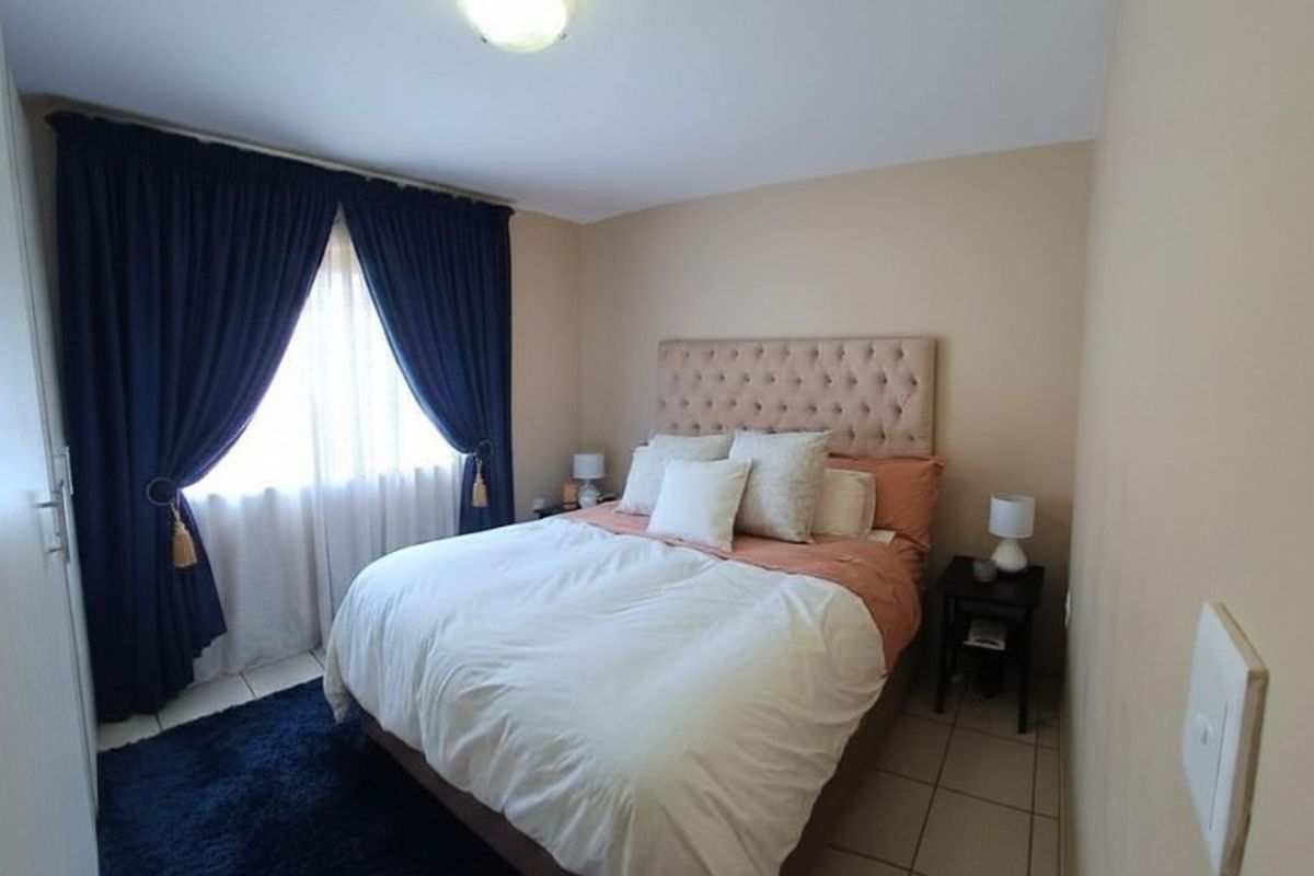 A well-maintained bedroom featuring tiled flooring, built-in cupboard space, and large windows dressed with curtains.