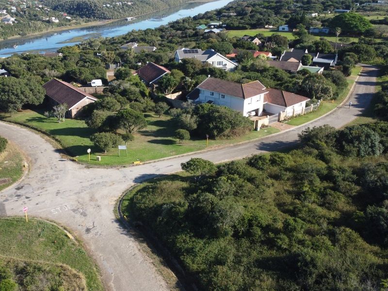 Aerial view of a residential property situated in a coastal neighborhood, featuring established landscaping and proximity to the river.