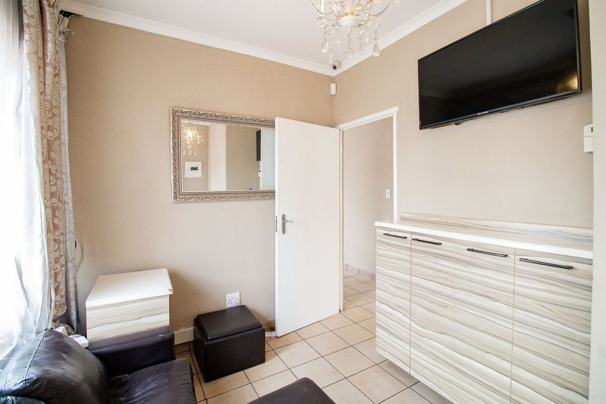 A functional living area featuring tiled flooring, built-in cabinetry, and a wall-mounted television setup.