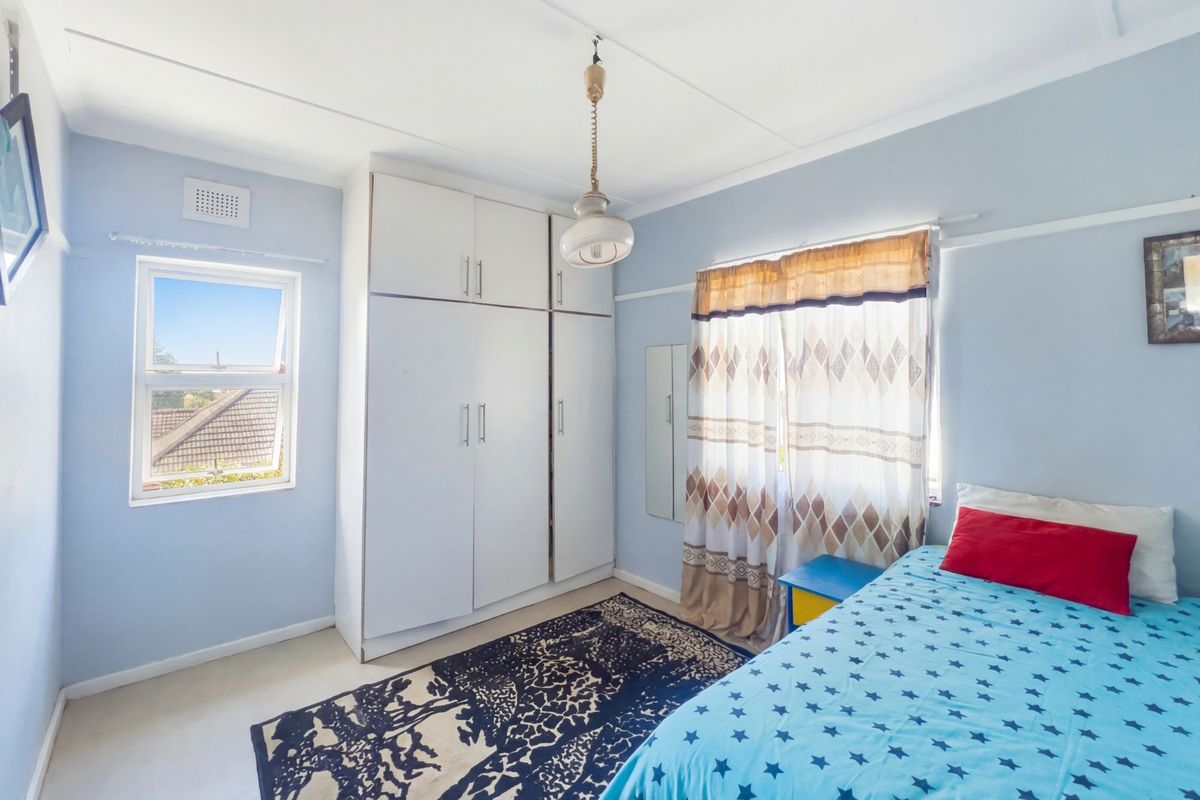 A bright bedroom featuring a built-in wardrobe, picture rails, and a casement window providing natural light.
