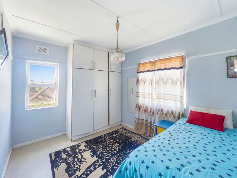 A bright bedroom featuring a built-in wardrobe, picture rails, and a casement window providing natural light.