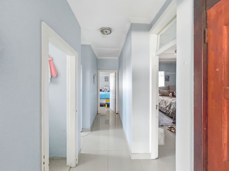 A functional hallway featuring tiled flooring and access to multiple rooms, showing signs of wear on the door frames and ceiling.