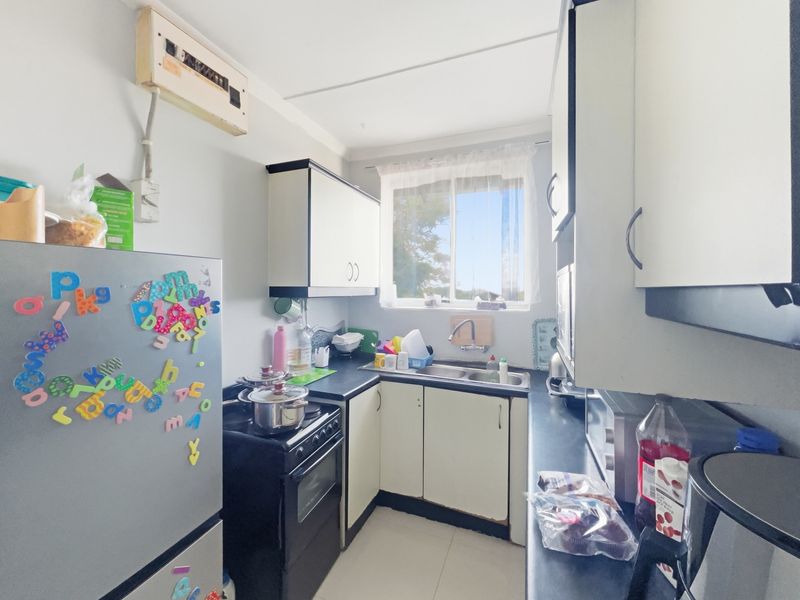 Compact kitchen featuring built-in cabinetry, a double sink, and an electric stove, offering a functional layout with potential for modernization.
