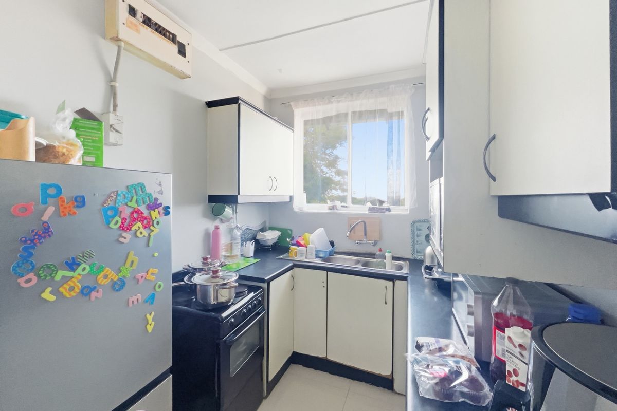Compact kitchen featuring built-in cabinetry, a double sink, and an electric stove, offering a functional layout with potential for modernization.