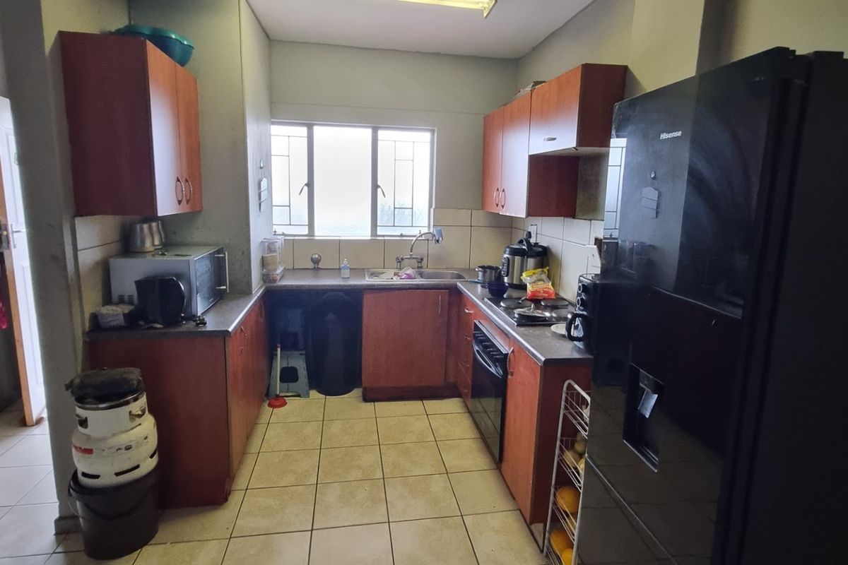 A functional kitchen featuring wood-tone cabinetry, tiled countertops, and a built-in oven, offering a practical layout for daily meal preparation.
