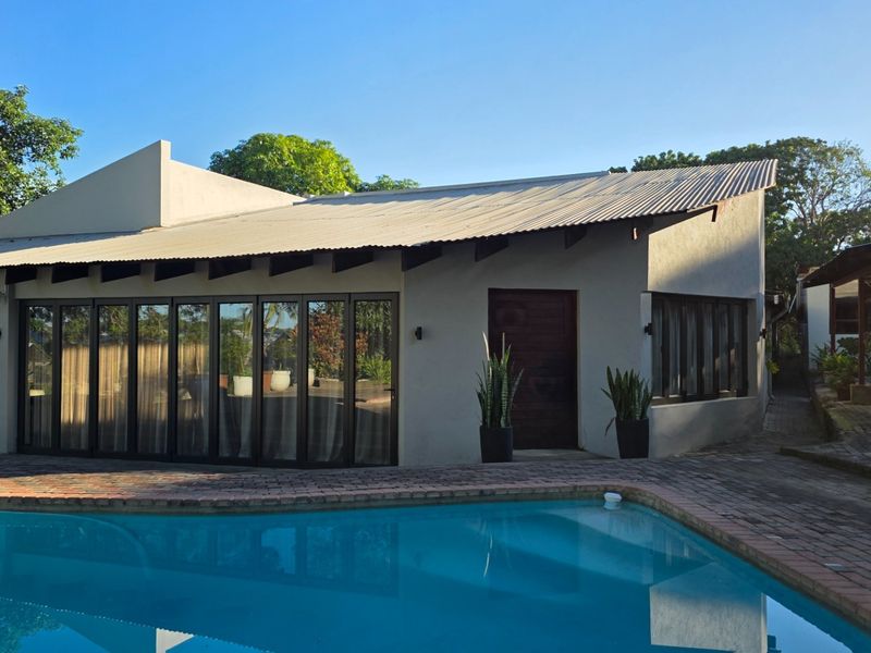 Exterior view of the farm property featuring a swimming pool, paved patio area, and large glass sliding doors leading into the main living space.