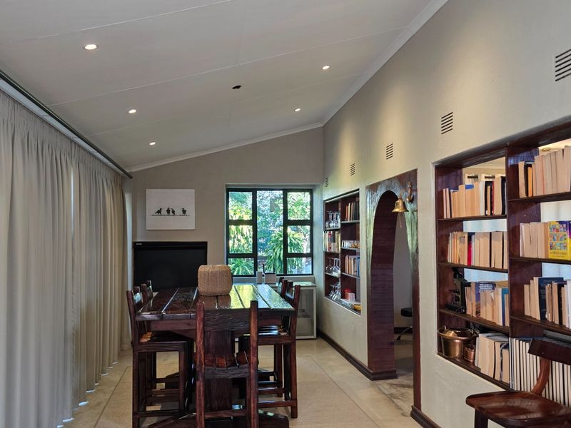 A spacious living area featuring built-in wooden shelving, recessed lighting, and a distinctive arched doorway leading to adjacent rooms.