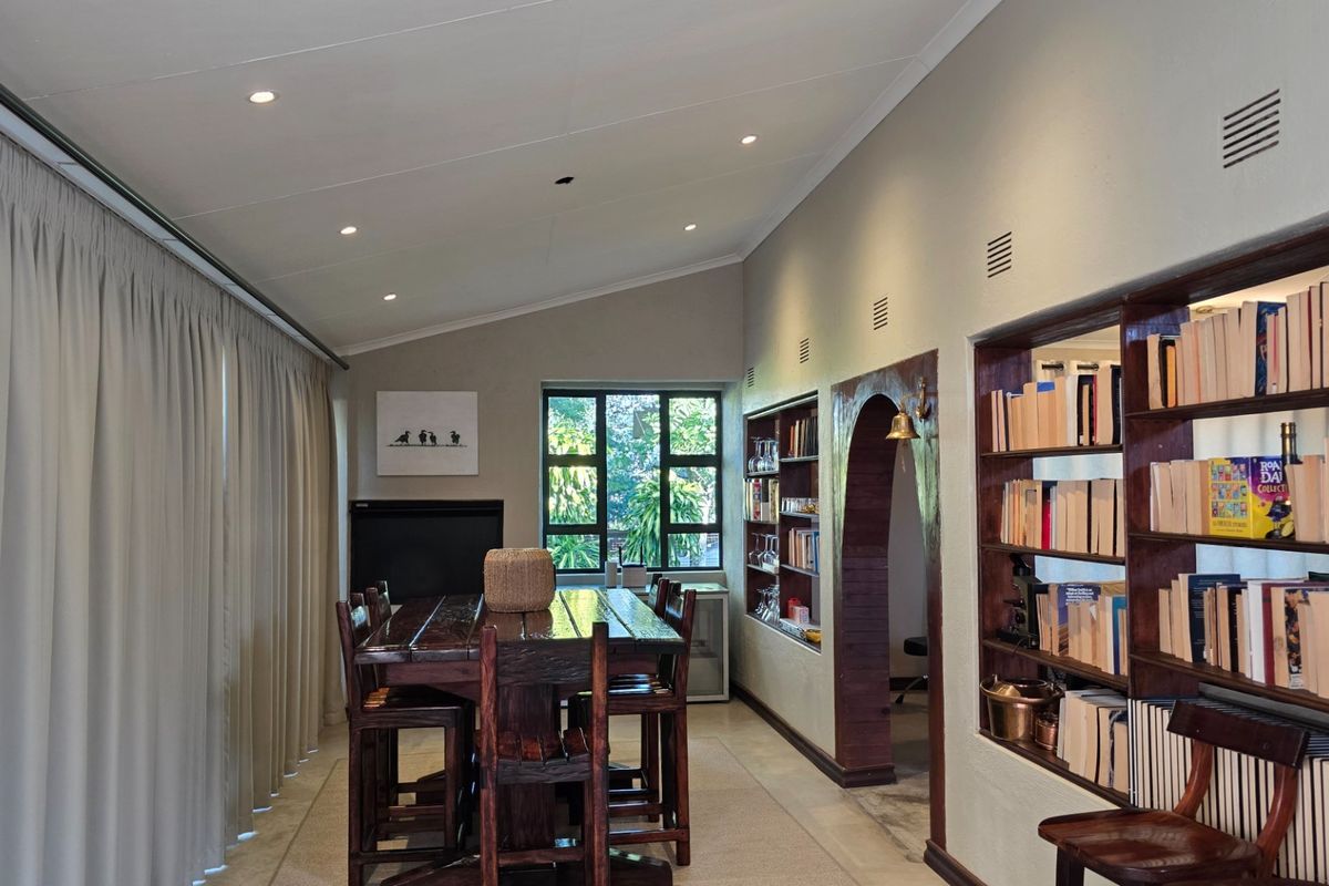 A spacious living area featuring built-in wooden shelving, recessed lighting, and a distinctive arched doorway leading to adjacent rooms.