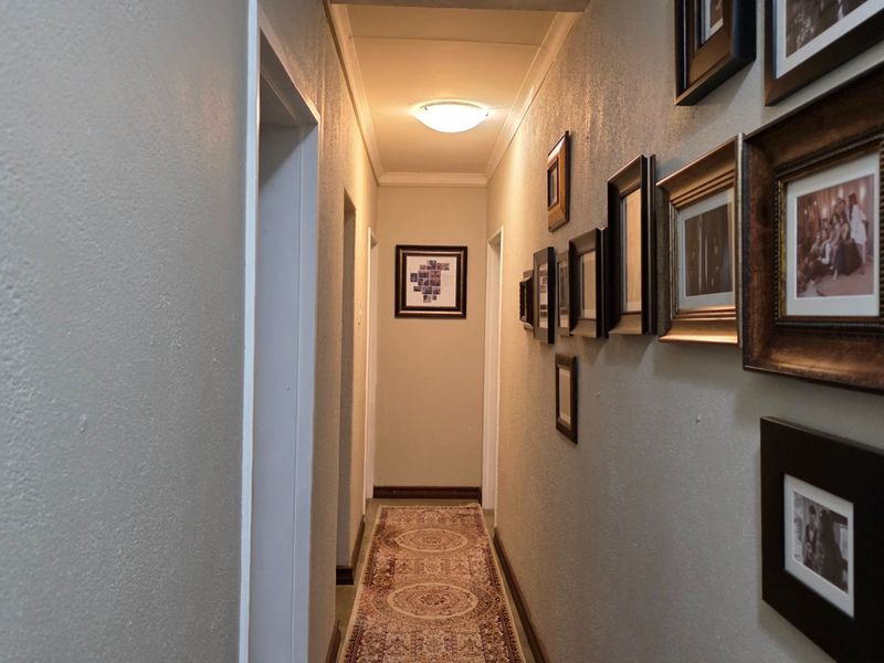 A functional interior hallway providing access to multiple rooms, featuring neutral wall finishes and a central ceiling light fixture.