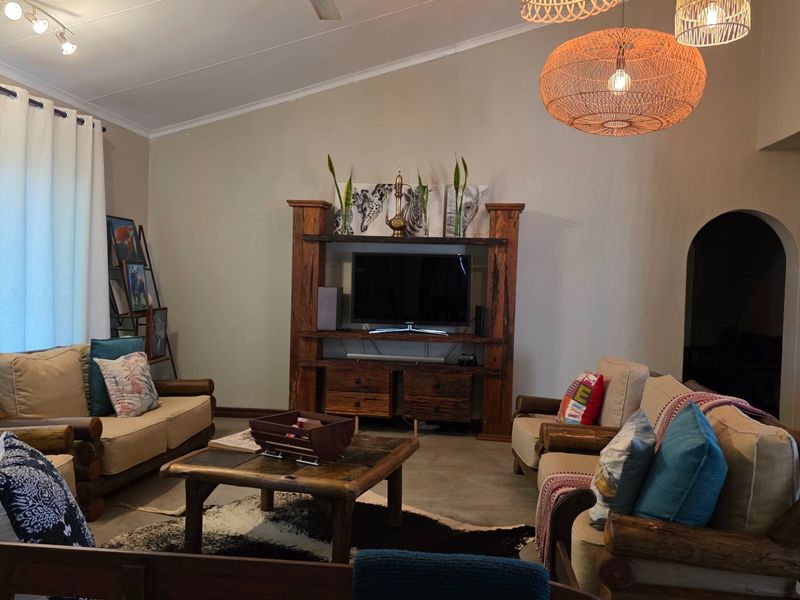 A rustic living room featuring a vaulted ceiling, exposed timber entertainment unit, and tiled flooring, creating a warm and inviting atmosphere.