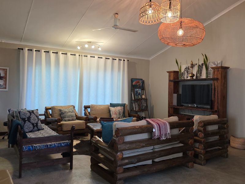 A spacious living room featuring a vaulted ceiling, ceiling fan, and large sliding glass doors that provide ample natural light.