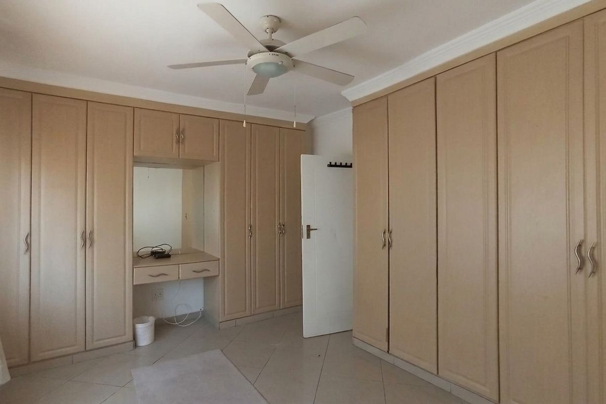 Bedroom featuring extensive built-in cabinetry with integrated vanity and ceiling fan, finished with tiled flooring.