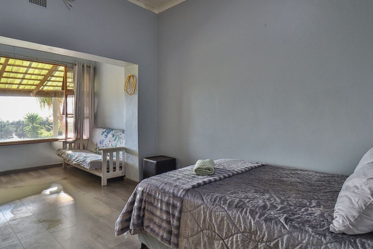 A spacious bedroom featuring a connected sunroom or seating area with large windows, providing natural light and a view of the garden.