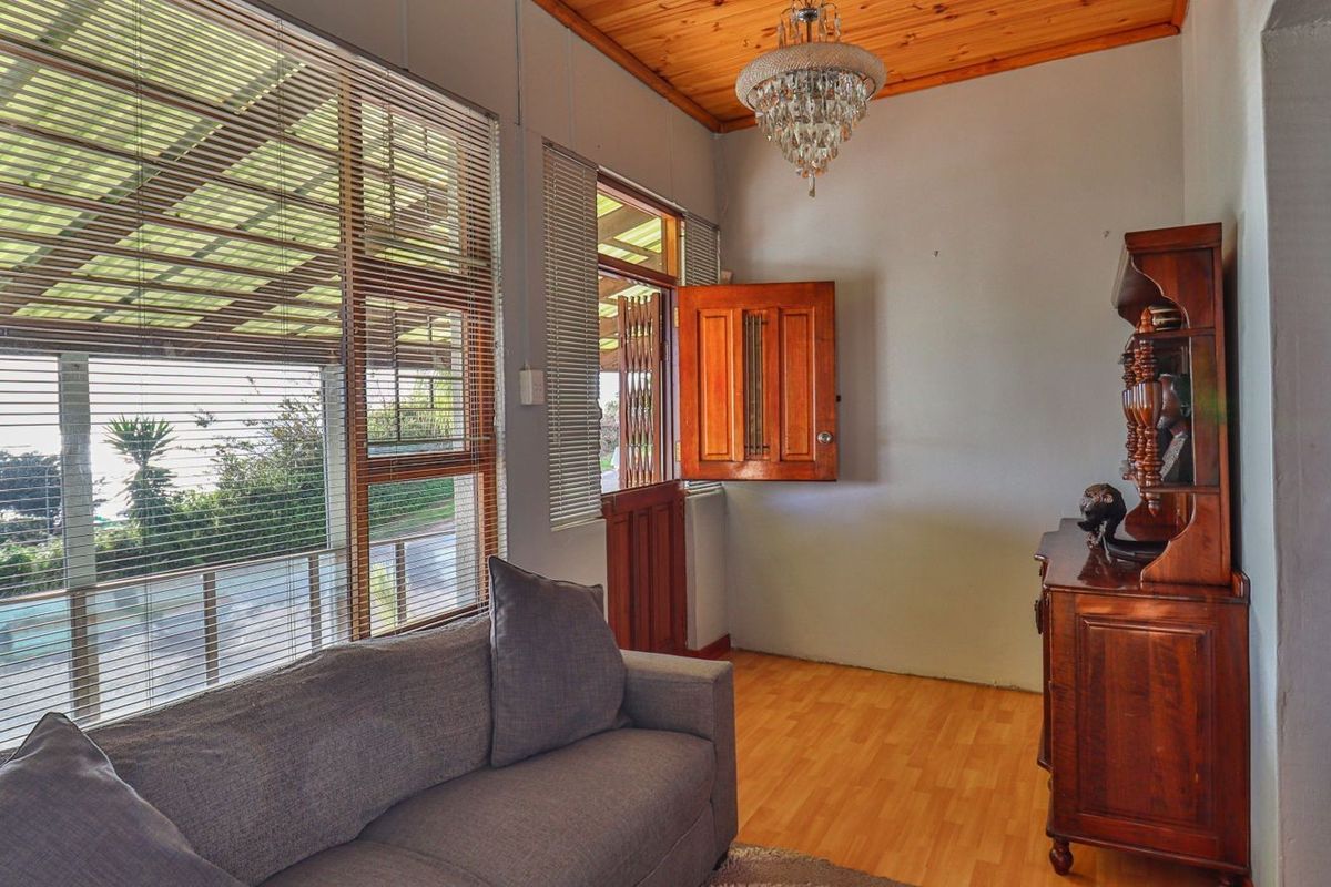 A living room featuring timber ceiling paneling, laminate flooring, large windows with venetian blinds, and a stable-style wooden door leading to the exterior.