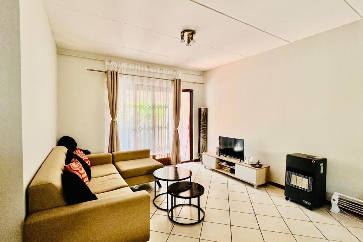 A bright living room featuring tiled flooring and a sliding glass door providing access to the outdoor area.