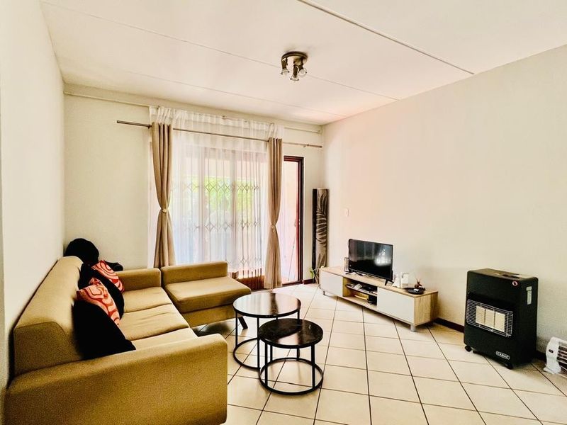 A bright living room featuring tiled flooring and a sliding glass door providing access to the outdoor area.