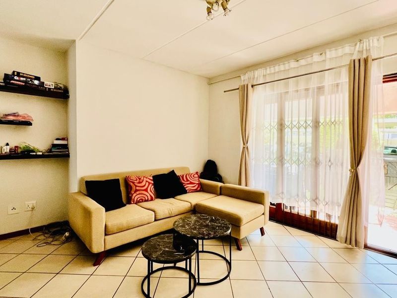 A living room featuring tiled flooring, built-in wall shelving, and sliding glass doors providing access to an outdoor area.