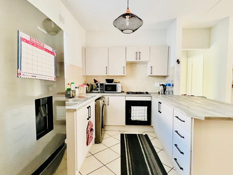 A functional kitchen featuring built-in cabinetry, a fitted oven and hob, tiled flooring, and a breakfast bar counter.