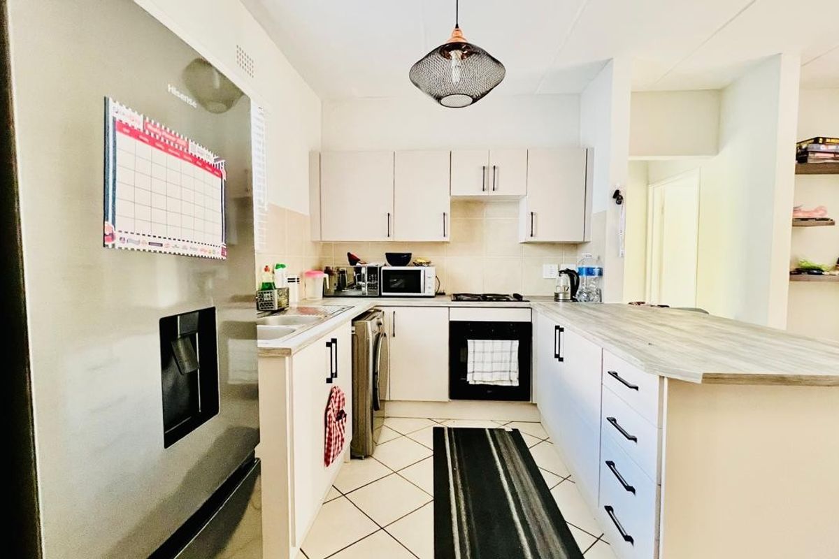 A functional kitchen featuring built-in cabinetry, a fitted oven and hob, tiled flooring, and a breakfast bar counter.