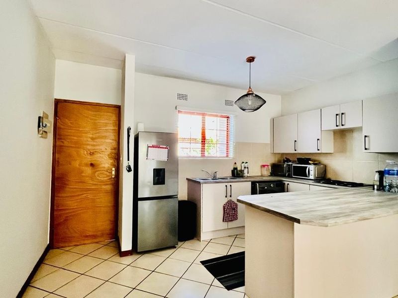 A functional kitchen featuring a breakfast bar, built-in cabinetry, tiled flooring, and a window providing natural light.