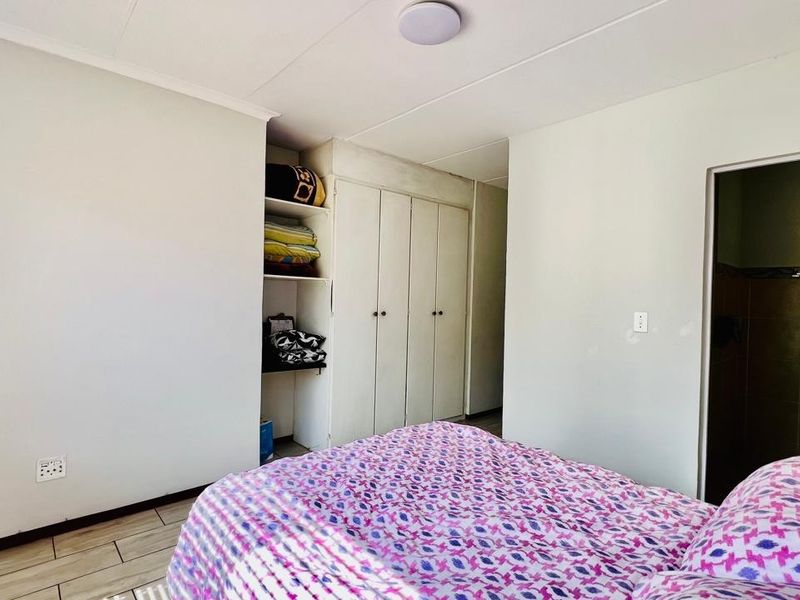 A bedroom featuring built-in cupboards with open shelving and tiled flooring, providing functional storage space within the apartment.