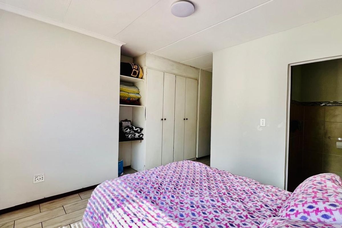 A bedroom featuring built-in cupboards with open shelving and tiled flooring, providing functional storage space within the apartment.