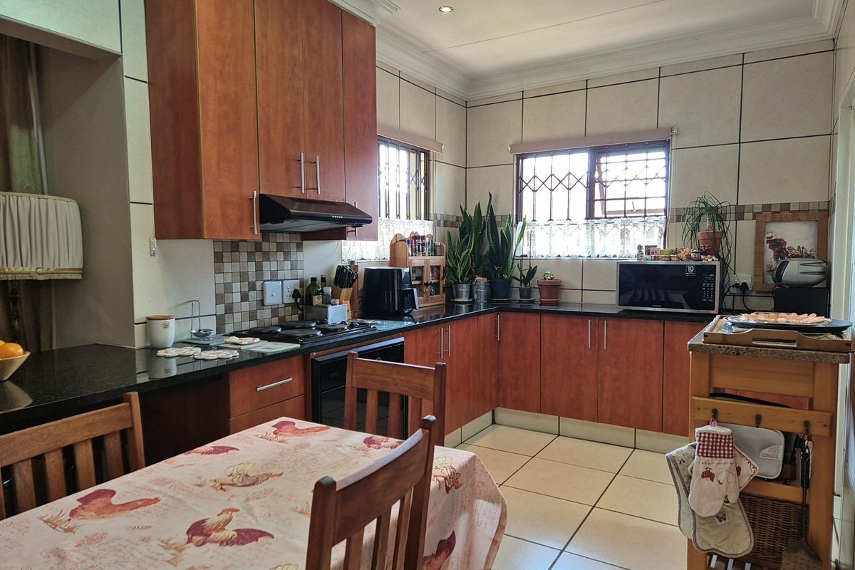 A functional kitchen featuring wooden cabinetry, dark granite countertops, tiled splashbacks, and integrated cooking appliances, offering a practical layout for daily meal preparation.