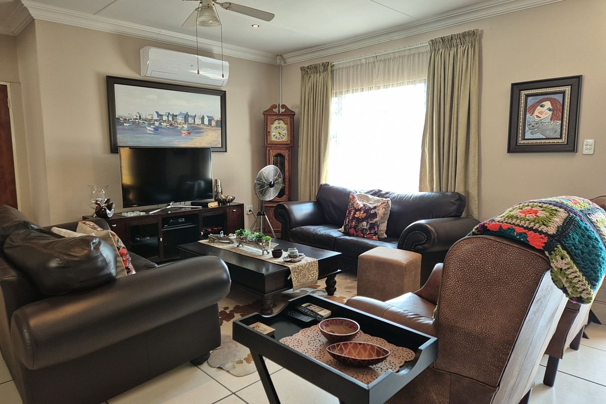A comfortable living room featuring tiled flooring, a ceiling fan, and a wall-mounted air conditioning unit.