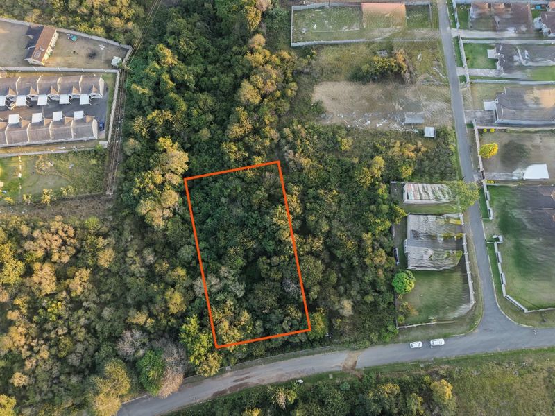 Aerial view of a vacant residential plot densely covered with mature trees and vegetation, highlighting the property boundaries.