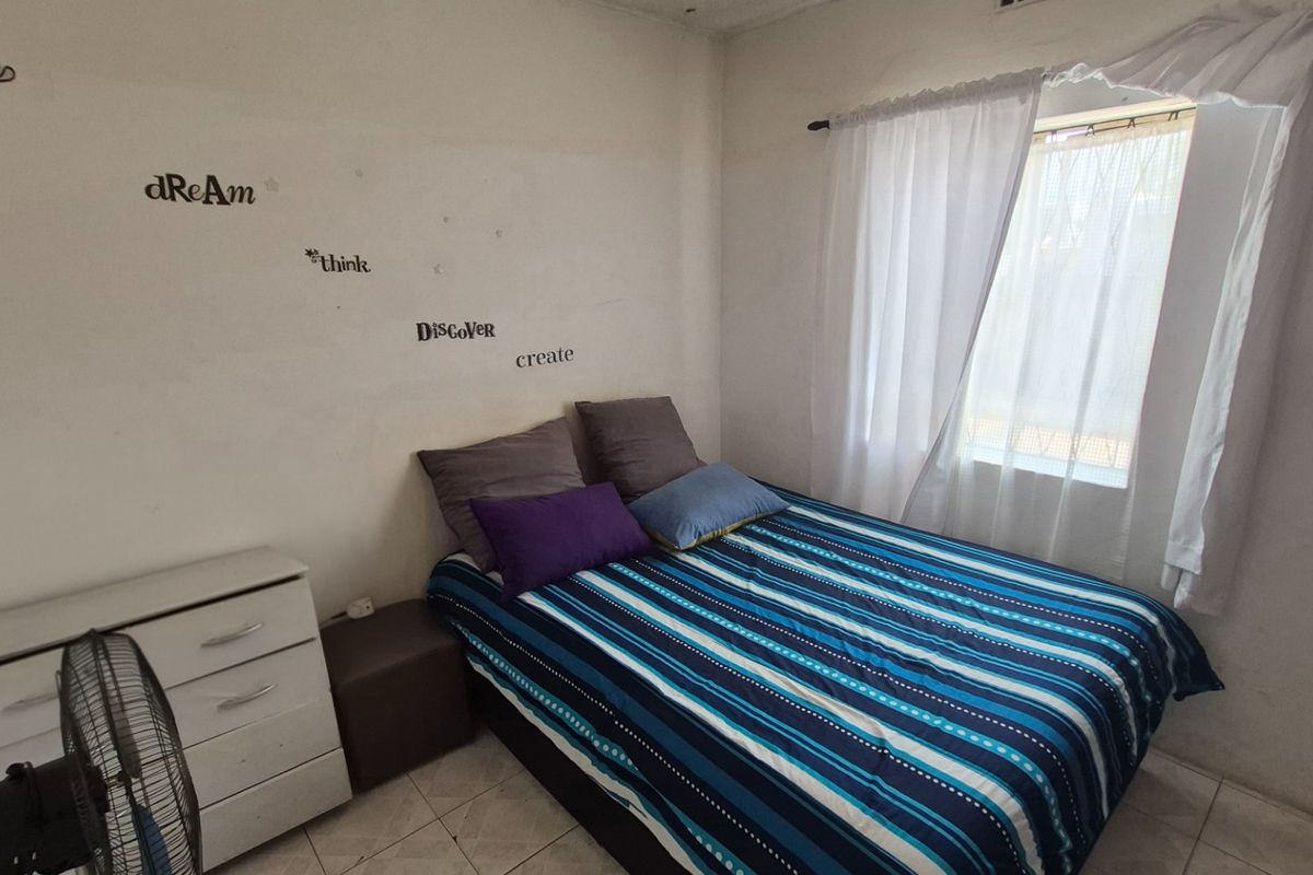 A compact bedroom featuring tiled flooring and a window with curtain fittings, providing a functional space for rest.