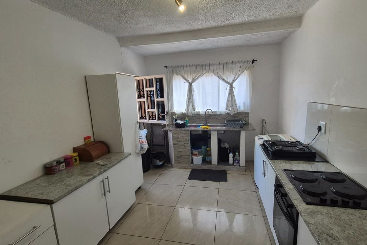 A functional kitchen featuring tiled flooring, granite-look countertops, a built-in oven, and a gas hob, with an open-style sink area.