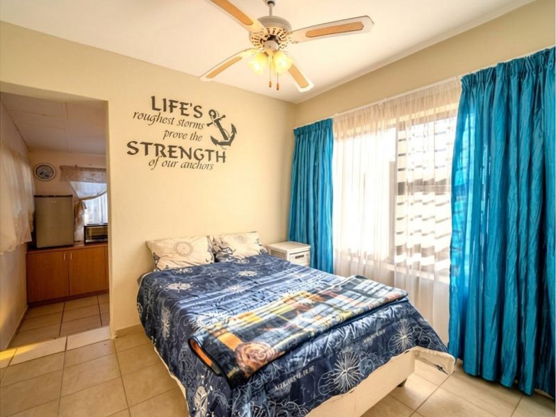 A bedroom featuring tiled flooring and a ceiling fan, with an adjoining space visible through the doorway.