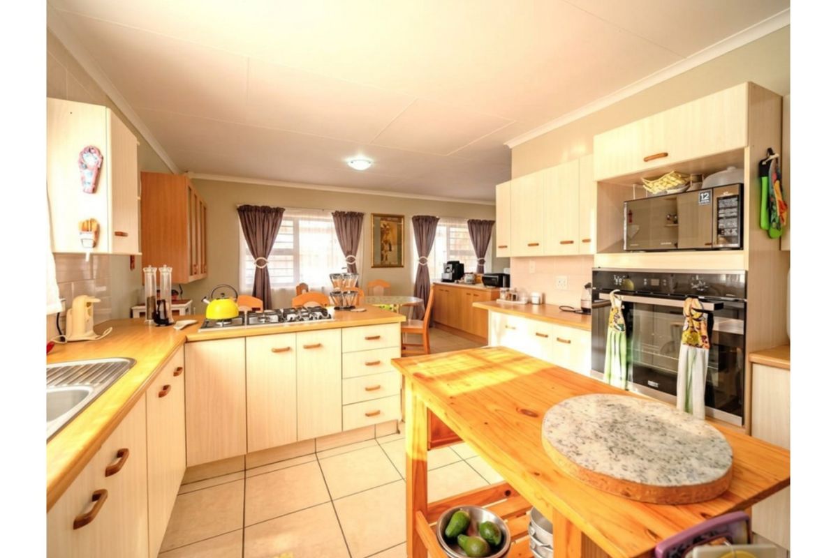 A functional kitchen featuring light-toned cabinetry, laminate countertops, a gas hob, and a built-in oven, with tiled flooring and an open-plan layout.